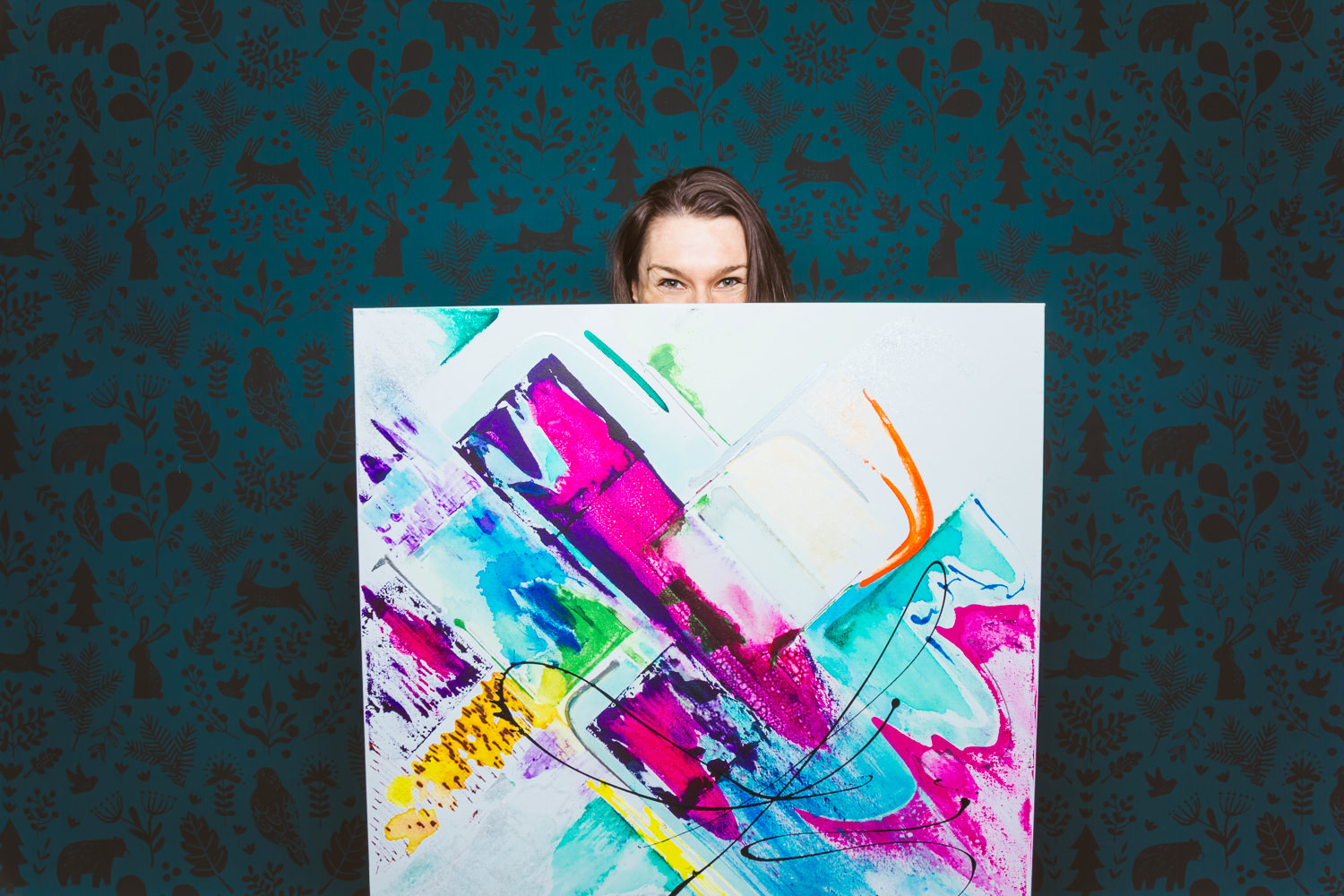 Marie-Josée Lépine, artiste peintre, derrière une toile, l'air espiègle